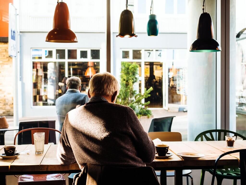 Photo of the back of a man reading in a cafe