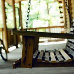 Photo of a chair swing on a porch with a bike leaning against the wall