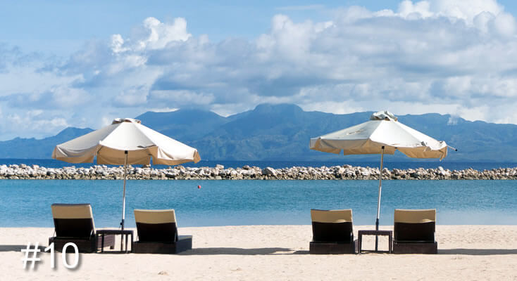 Photo of four chairs under two umbrellas overlooking the ocean and mountains