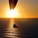Photo of two people parasailing over the ocean in the sunset