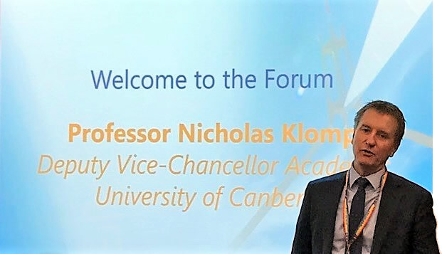 Photo of Professor Nicholas Klomp standing in front of a powerpoint screen