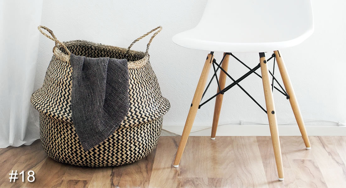 Photo of a white chair with a woven basket next to it with a throw hanging out of it