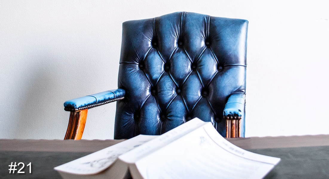 Photo of a blue leather studded desk chair behind a desk with a book on it