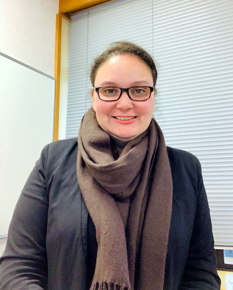 Photograph of Rossana-Couto-Mason in the office wearing glasses and a scarf