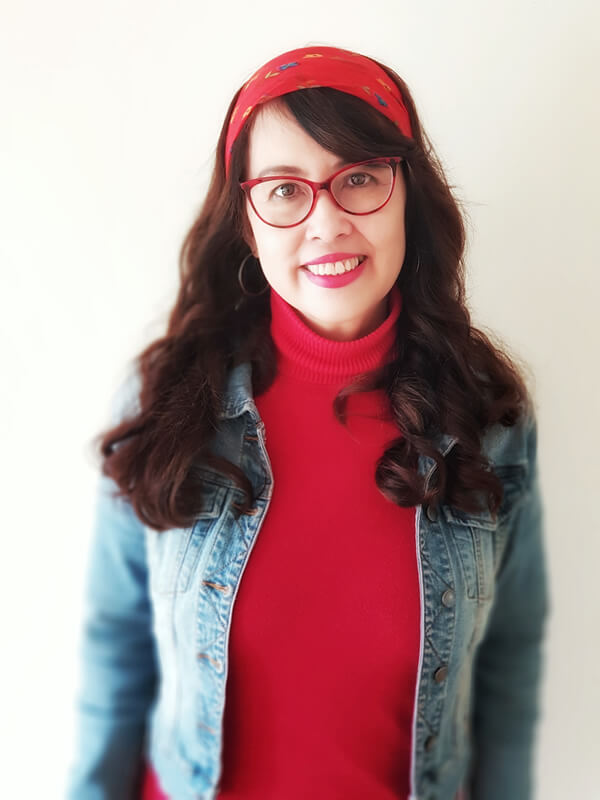 Photo of Grace Corpuz wearing a red top and headband, and a denim jacket and glasses.