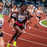 Photo of female athletes sprinting on a race track.