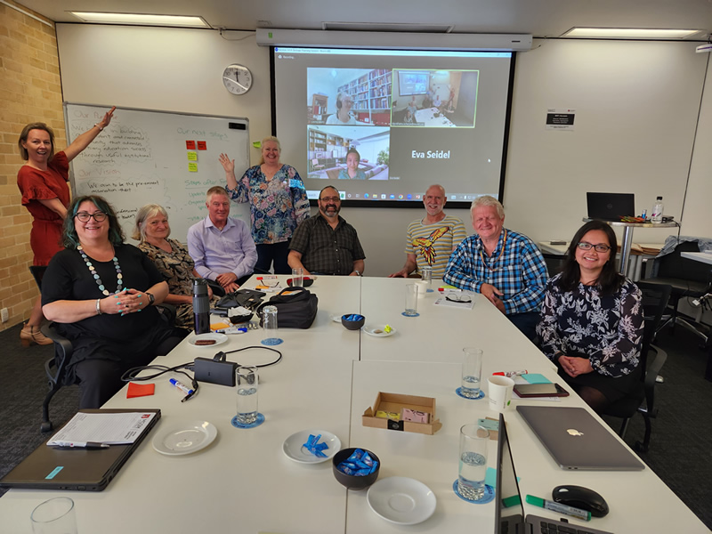 Photo of the AAIR Executive Committee at the conclusion of the 2023 strategic planning session. All committee members are around a boardroom table, with some joining via Zoom on a screen in the background.