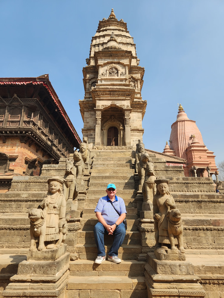 Photo of Andrew Bradshaw sitting on steps of an ancient building at Bhaktapur village.
