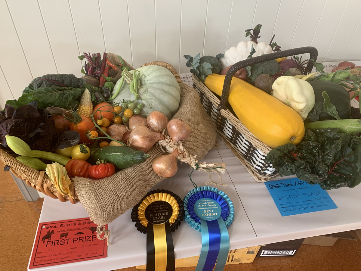 Photo of fresh produce on a table at a show with competition winning ribbons and certificates.